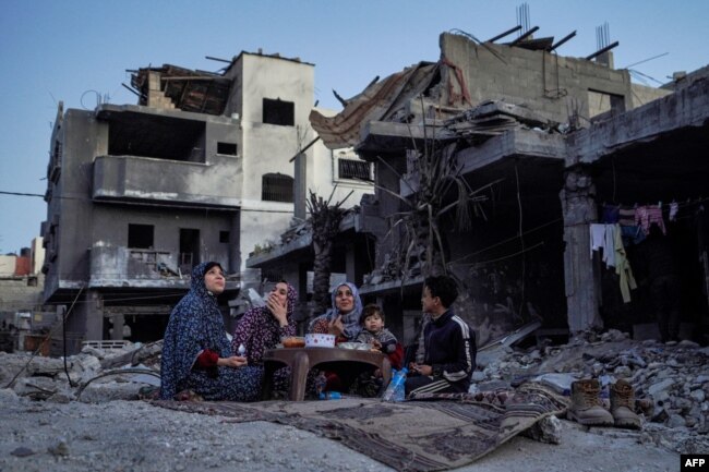 The Palestinian Al-Naji family eats an iftar meal, the breaking of fast, amidst the ruins of their family house, on the first day of the Muslim holy fasting month of Ramadan, in Deir el-Balah in the central Gaza Strip on March 11, 2024.