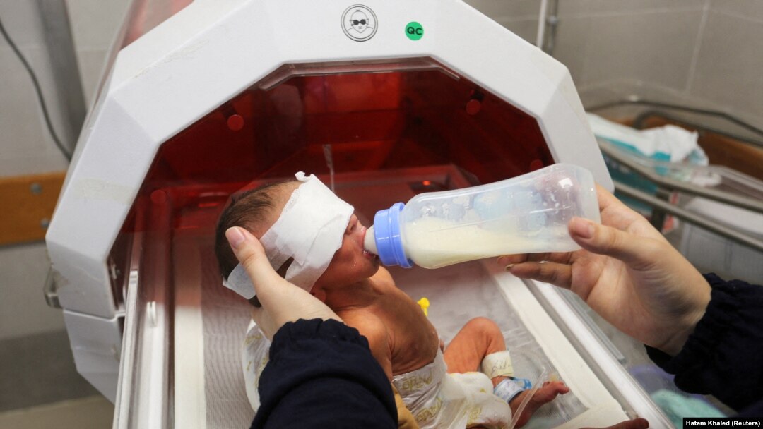 Seorang bayi prematur yang dievakuasi dari inkubator Rumah Sakit Al Shifa di Kota Gaza disusui saat tiba di rumah sakit di Rafah, di selatan Jalur Gaza, 19 November 2023. (Foto: REUTERS/Hatem Khaled)