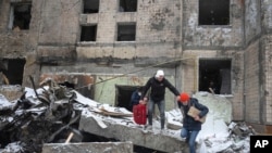 La gente sale con sus pertenencias de un edificio de apartamentos destruido después del ataque ruso del martes en Kiev, Ucrania, el miércoles 3 de enero de 2024. (Foto AP/Efrem Lukatsky)