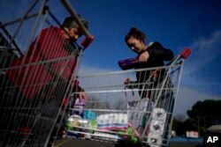 La uruguaya Diana Rocco descarga un carrito de compras lleno en su automóvil frente a un supermercado en Gualeguaychú, en la provincia de Entre Ríos, Argentina, el viernes 30 de junio de 2023.