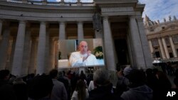 FILE - Pope Francis appears on a giant monitor set up in St. Peter's Square at The Vatican, Nov. 26, 2023, as he blesses the faithful gathered in the square.
