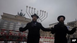 FILE - Two rabbis dance in front of a giant Hanukkah Menorah, after it was set up by the Jewish Chabad Educational Center ahead of the Jewish Hanukkah holiday, in front of the Brandenburg Gate in central Berlin, Dec. 6, 2023. 