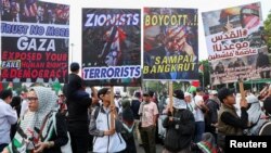 Warga memegang plakat dalam unjuk rasa pro-Palestina di Jakarta, 9 Juni 2024, di tengah konflik yang berlangsung antara Israel dan Hamas. (Foto: REUTERS/Ajeng Dinar Ulfiana)