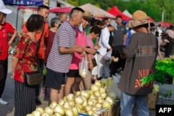 People shop for food at an open air market in Shenyang, in China's northeast Liaoning province, on July 10, 2023.