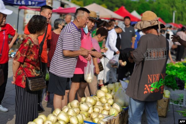 People shop for food at an open air market in Shenyang, in China's northeast Liaoning province, on July 10, 2023.