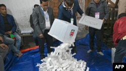 Election officials pour ballot papers from a ballot box for counting at a polling booth in Dhaka, Bangladesh, Jan. 7, 2024. 