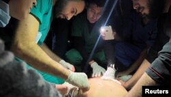 Medical services use phone flashlights to assist a Palestinian wounded in Israeli strikes at the Indonesian hospital after Al Shifa hospital has gone out of service amid Israeli ground offensive, in the northern Gaza Strip, Nov. 16, 2023.