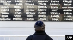 FILE - A man prays in front of the Argentine Israelite Mutual Association Jewish community center during the commemoration of the anniversary of the terrorist bombing that killed 85 people and injured more than 300, in Buenos Aires, July 18, 2017.