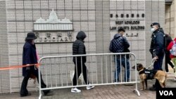軍裝警員牽著警犬監察進入西九龍裁判法院大樓，旁聽香港壹傳媒創辦人黎智英國安案的市民。（美國之音湯惠芸）