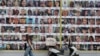 FILE - A woman walks past a wall displaying posters of hostages, most of whom were kidnapped during the deadly Oct. 7 attack by Hamas, in Tel Aviv, Aug. 18, 2024.