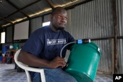 FILE - Derrick Mesulamu, the county director for the Bucket Ministry, a Christian nonprofit organization, demonstrates how to use a bucket filter to locals in Athi River, Machakos county, Kenya, Oct. 17, 2023.