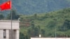 FILE - Myanmar government troops stand on a rooftop on the Myanmar side, near a Chinese flag from the Chinese border town of Nansan in southwestern China's Yunnan province, Aug 30, 2009. 