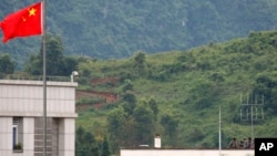 FILE - Myanmar government troops stand on a rooftop on the Myanmar side, near a Chinese flag from the Chinese border town of Nansan in southwestern China's Yunnan province, Aug 30, 2009. 