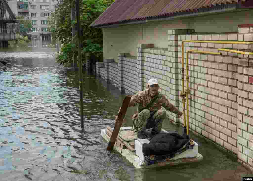 A local resident floats on a homemade raft at a flooded street during an evacuation from a flooded area after the Nova Kakhovka dam breached, in Kherson, Ukraine, June 8, 2023.