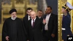 Russian President Vladimir Putin, center, welcomes Iranian President Ebrahim Raisi, left, for the talks at the Kremlin in Moscow, Dec. 7, 2023. (Pool Photo via AP)