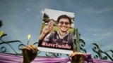 FILE - An activist holds up a picture of abducted Thai activist Wanchalearm Satsaksit as people gather in support of him during a protest calling for an investigation in front of the Government house in Bangkok, Thailand, June 12, 2020.