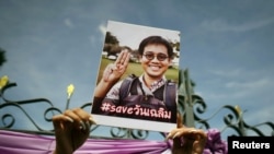 FILE - An activist holds up a picture of abducted Thai activist Wanchalearm Satsaksit as people gather in support of him during a protest calling for an investigation in front of the Government house in Bangkok, Thailand, June 12, 2020.