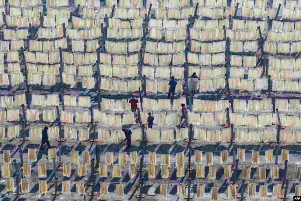 Селаните висат тестенини за да се исушат на поле додека се подготвуваат за претстојните пазари на Лунарната Нова Година во Хуаиан, во источната кинеска провинција Џиангсу.