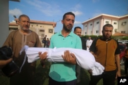 A relative carries the body of Amir Ganan, who was killed in an Israeli airstrike, during his funeral in Khan Younis, Gaza Strip, Oct. 10, 2023.