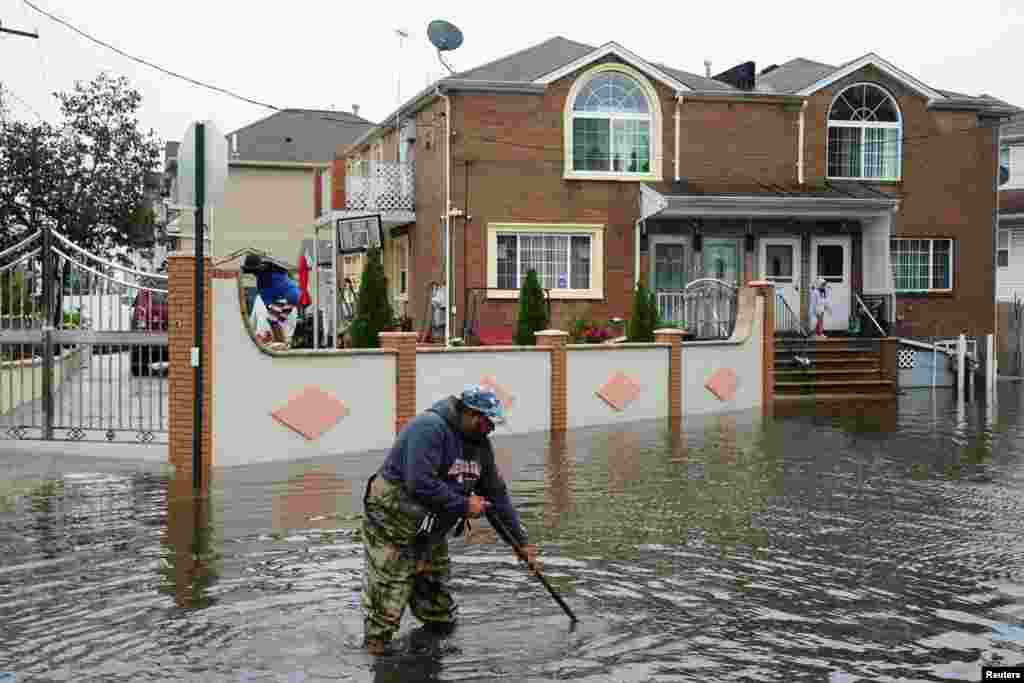 Um residente tenta desentupir folhas e outros detritos dos buracos de drenagem no bairro de Hamilton Beach, no distrito de Queens, na cidade de Nova Iorque, a 29 de setembro de 2023.