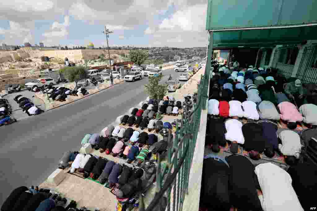 Muslim Palestinians take part in Friday Noon prayers in East Jerusalem neighborhood of Ras al-Amud, following age restrictions by Israeli security to above 50 years old for worshippers wanting to access the Al-Aqsa Mosque compound, top background, amid the ongoing battles between Israel and the Palestinian group Hamas.&nbsp;