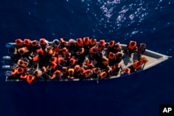 Migrants from Eritrea, Libya and Sudan sail a wooden boat before being assisted by aid workers of the Spanish NGO Open Arms, in the Mediterranean sea, about 30 miles north of Libya, June 17, 2023.