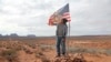 FILE - In this Oct. 25, 2018, photo, Brandon Nez displays his flag near his jewelry stand in Monument Valley, Utah. 