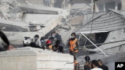 Emergency services work at a building hit by an air strike in Damascus, Syria, Jan. 20, 2024. Syrian and Iranian state media say an Israeli strike on t Damascus killed five Iranian advisers.