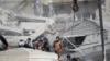 Emergency services work at a building hit by an air strike in Damascus, Syria, Jan. 20, 2024. Syrian and Iranian state media say an Israeli strike on the Syrian capital killed five Iranian advisers. 