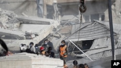 Emergency services work at a building hit by an air strike in Damascus, Syria, Jan. 20, 2024. Syrian and Iranian state media say an Israeli strike on the Syrian capital killed five Iranian advisers. 