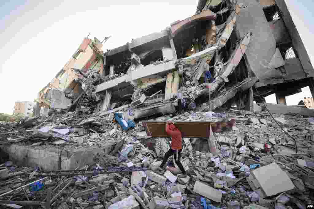Palestinians carrying some belongings walk amid the rubble of destroyed buildings in Al-Zahra on the southern outskirts of Gaza City as a truce between Israel and Hamas entered its third day.