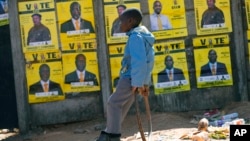 A young boy leans near campaign posters with images of male candidates in Harare, Zimbabwe, July 16 2023.