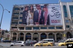 Sebuah poster bergambar, dari kanan: Raja Abdullah II, Putra Mahkota Hussein, arsitek Saudi Rajwa Alseif dan Ratu Rania, digantung di depan sebuah gedung di ibu kota Amman, Yordania, Rabu, 31 Mei 2023. (AP/Nasser Nasser)