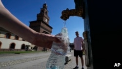 FILE - Seorang wisatawan mengisi botol plastik dengan air dari keran air umum di Kastil Sforzesco, Milan, Italia, 25 Juni 2022. (AP/Luca Bruno)