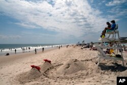 Para pengunjung pantai menikmati selancar di pantai Long Island, New York di mana serangan hiu terhadap manusia semakin sering terjadi.