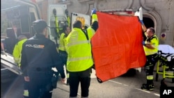 Paramedics cover the view of an ambulance parked on the site of a shooting in Madrid, Spain, Nov. 9, 2023. 