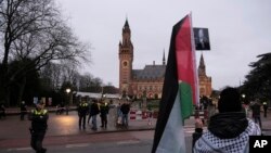 Seorang pengunjuk rasa berdiri di luar Mahkamah Internasional (ICJ) sebelum sidang di Den Haag, Belanda, Jumat, 12 Januari 2024. Pertarungan hukum mengenai apakah perang Israel melawan Hamas di Gaza merupakan genosida dibuka pada Kamis di Pengadilan Dunia. (AP/Patrick Post)