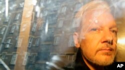 FILE - Buildings are reflected in the window as WikiLeaks founder Julian Assange is taken from court, where he appeared on charges of jumping British bail, in London, on May 1, 2019.