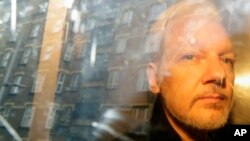 FILE - Buildings are reflected in the window as WikiLeaks founder Julian Assange is taken from court in London on May 1, 2019. Assange's possible final appeal on extradition to the United States will take place in Britain's High Court in February 2024.