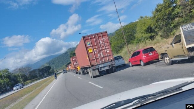 Doble fila de autos y camiones que esperan para surtir combustible obstaculizan el tránsito en una importante autopista en Venezuela.