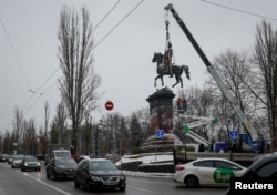 Municipal workers dismount a monument to Mykola Schors, a Soviet field commander during the Russian Civil War, in Kyiv, Ukraine, Dec. 9, 2023.