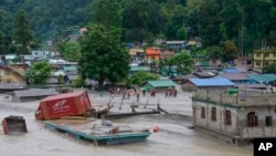 A vehicle that got washed away lies atop a submerged building after flash floods triggered by a sudden heavy rainfall swamped the Rangpo town in Sikkim, India, Oct.5. 2023. 