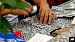 ရန်ကုန်မြို့ပေါ်ရှိ နိုင်ငံခြားငွေလဲလှယ်ရေးလုပ်ငန်းတခုမှာတွေ့ရတဲ့ အမေရိကန်ဒေါ်လာ ၁၀၀ တန်တချို့ (စက်တင်ဘာ ၁၅၊ ၂၀၁၆)
