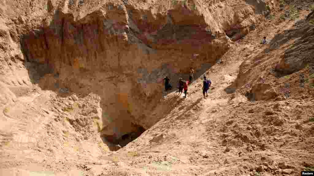 Palestinians gather to inspect the damage after Israeli forces withdrew from the area following a ground operation amid the ongoing conflict between Israel and Hamas, in Khan Younis, in the southern Gaza Strip.