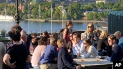 People enjoy drinks and snacks in the evening sun on a terrace overlooking Stockholm, on May 30, 2023.