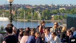 Sejumlah orang tampak menikmati minuman dan snacks di Stockholm, pada 30 Mei 2023. (Foto: AP/Karl Ritter)