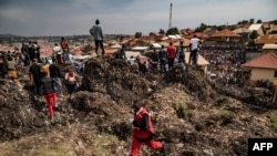 Para petugas dari tim Palang Merah Uganda berlalri untuk meminta bantuan dalam upaya pencarian korban longsoran sampah di Kampala, Uganda, pada 10 Agustus 2024. (Foto: AFP/Badru Katumba)