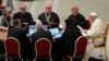 Pope Francis, right, speaks with a group of voting members during the opening session of the 16th General Assembly of the Synod of Bishops in the Paul VI Hall at the Vatican, Oct. 4, 2023