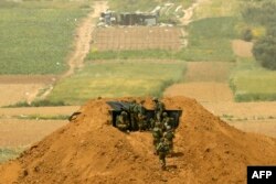 FILE - Israeli soldiers gather at a position over an earth barrier along the border with the Gaza Strip in the southern Israeli kibbutz of Nahal Oz, March 30, 2019.