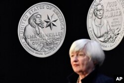 The Wilma Mankiller, left, and Nina Otero-Warren quarters, are displayed above Secretary of the Treasury Janet Yellen at the Denver Mint, March 11, 2022. The mint is one of two locations manufacturing coins for the American Women Quarters Program.